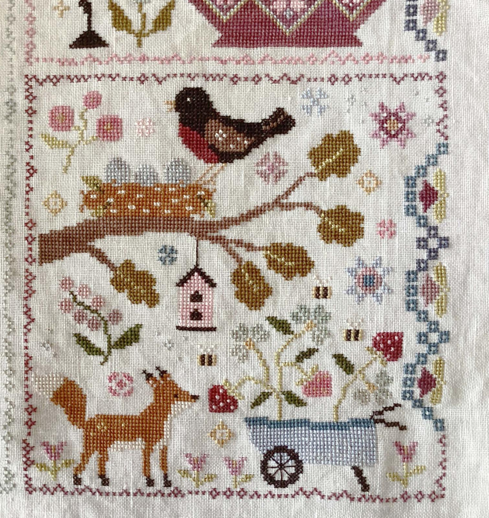 Cross-stitched design with animals and nature elements on a white background