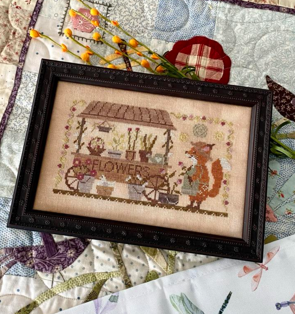 Framed cross-stitch art with a fox and flower theme on a quilt background, featuring 'Fox and Flower Co. Nashville Exclusive' text.